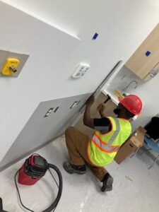 A construction worker is working on a wall in a room.