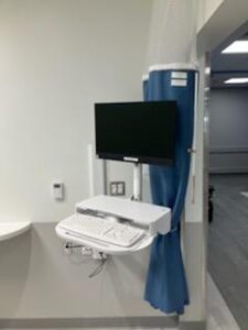 A hospital room with a computer and a monitor.