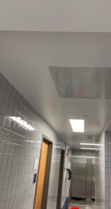 A bathroom with a tiled ceiling and a red floor mat.