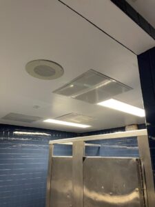 A bathroom with two stalls and a ceiling fan.