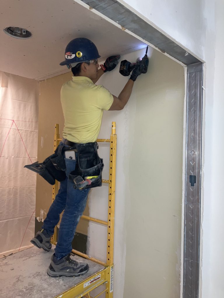 A construction worker drilling a hole in the ceiling