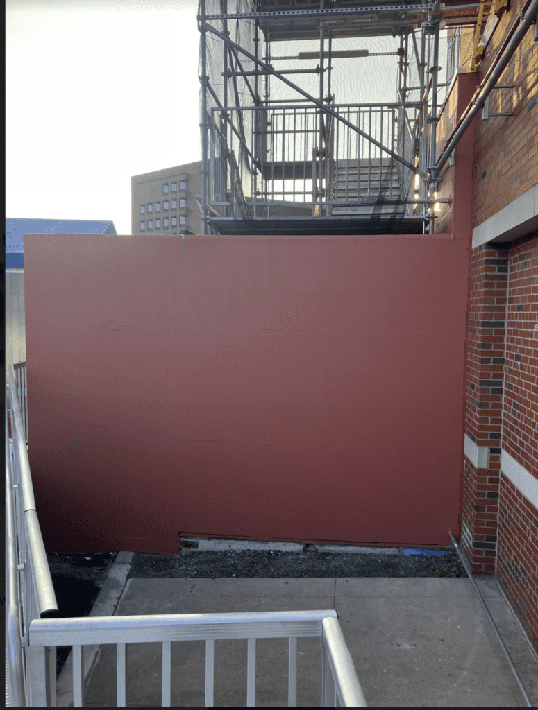 A red wall with scaffolding in front of it.