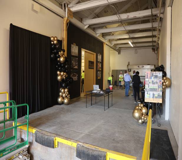 A room with black and gold balloons in a warehouse.