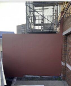 A building with scaffolding and a red wall.