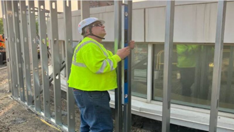 A construction worker standing next to a metal frame.