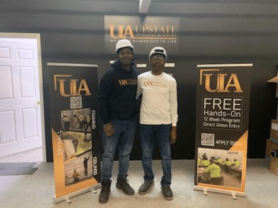 Workers posing in front of program signs.