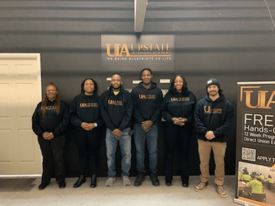 Six people standing together, wearing hoodies