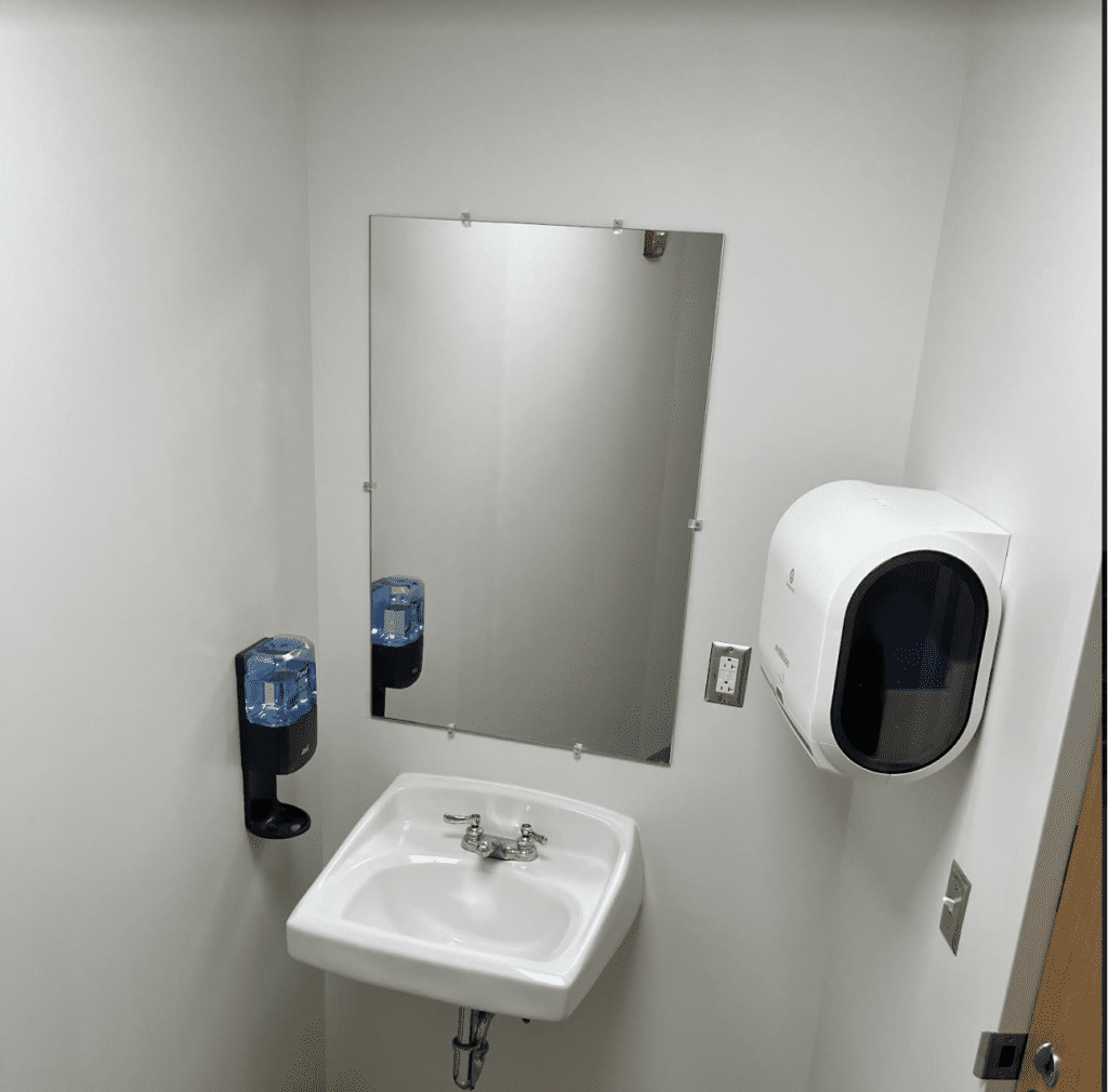 Bathroom sink with mirror and dispensers.